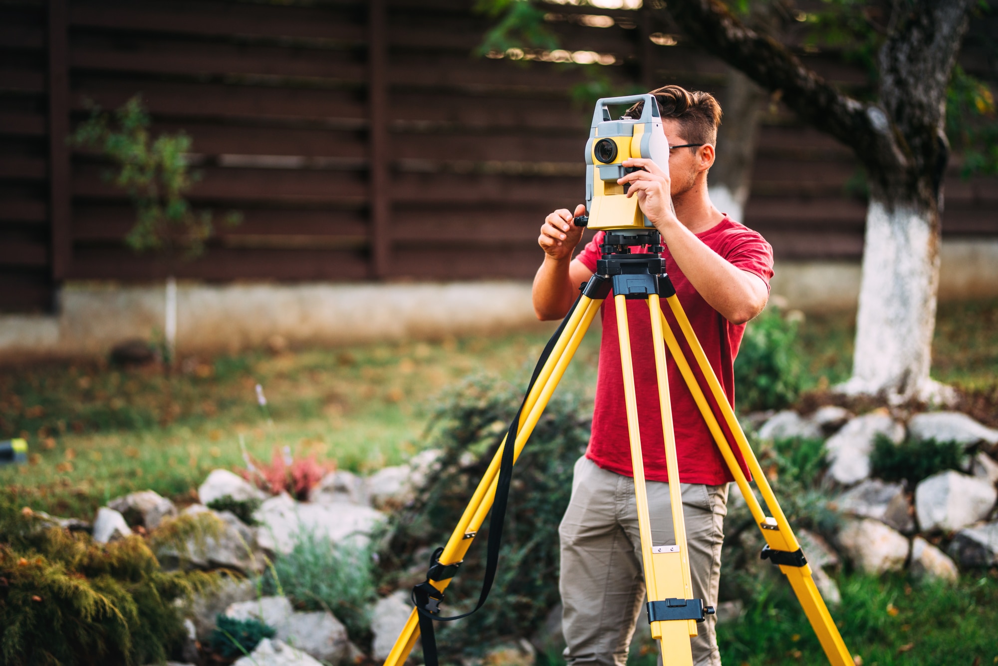 Man standing in front of surveyor's tripod, preparing for land surveying.