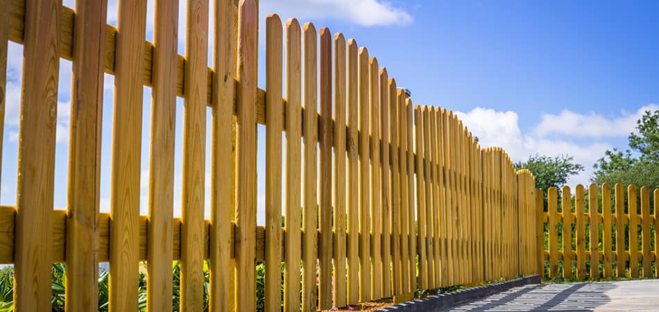 a wooden fence with blue sky and clouds