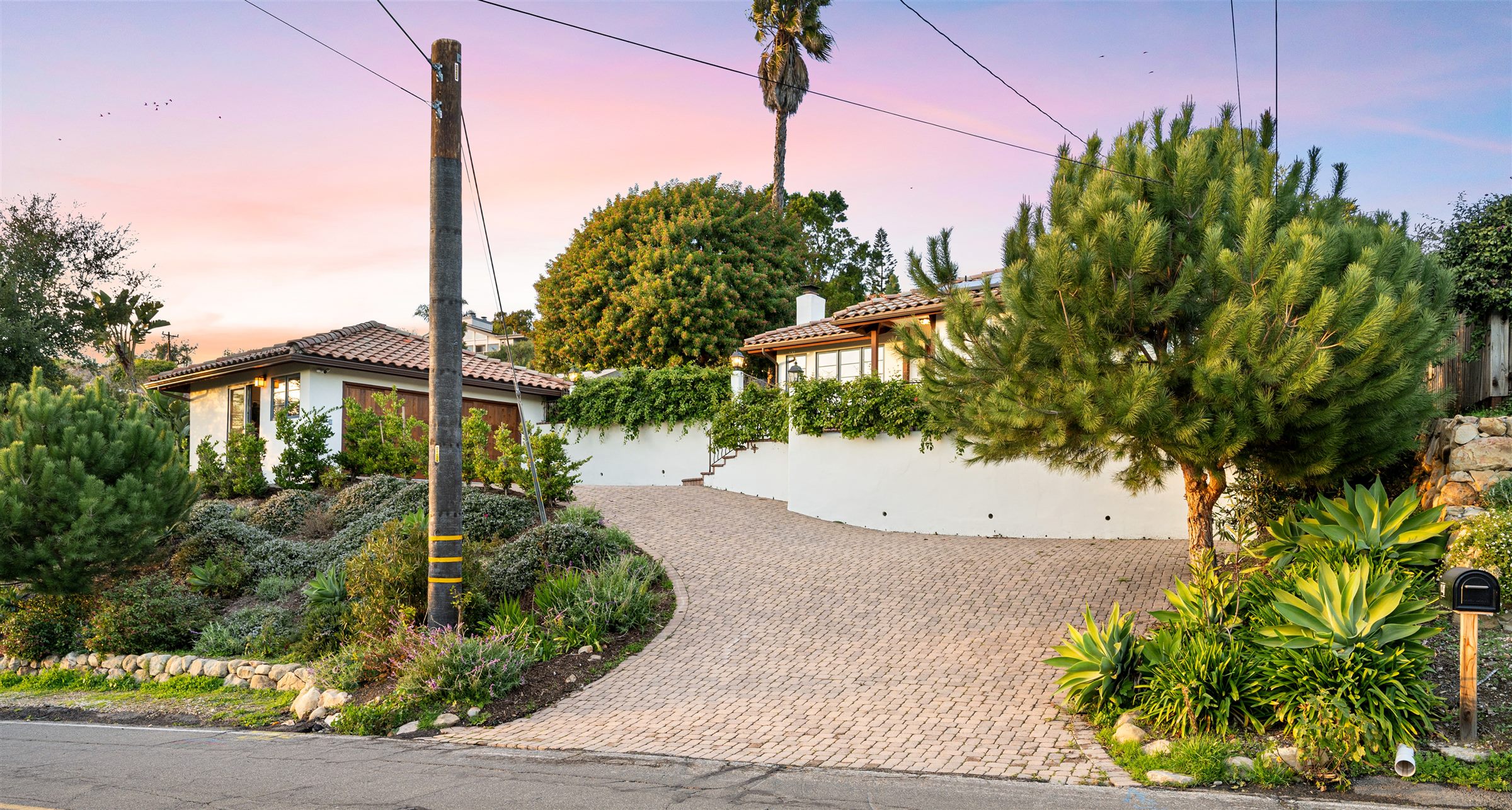 Paver driveway curving up from the street to a hillside house